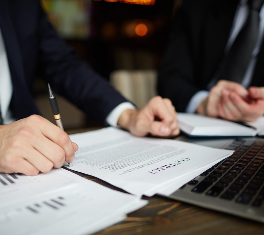 Businessman Reading Contract Closeup Closeup portrait of unrecognizable successful businessman wearing black formal suit reviewing documents and signing contract during meeting